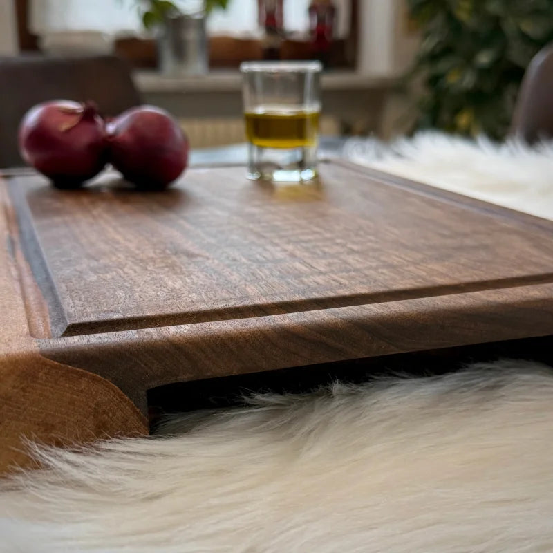 Nussbaum Massivholz Steak-Brett mit Saftrille auf weißem Fell für stilvolles Kochen