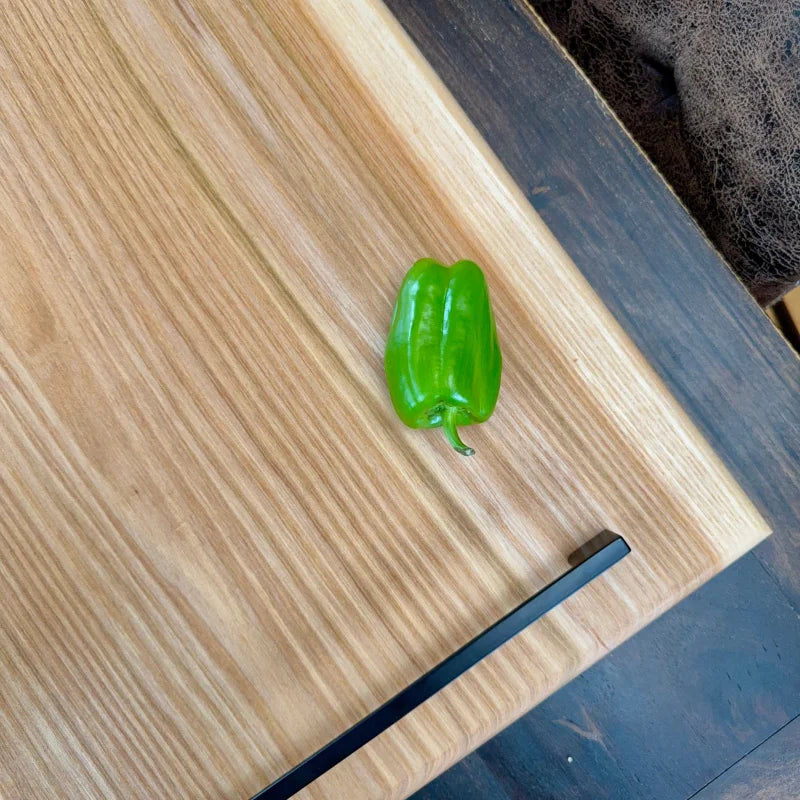 Frischer grüner Paprika auf einem Holz Servierbrett mit Füßen, perfekt für Grillmeister