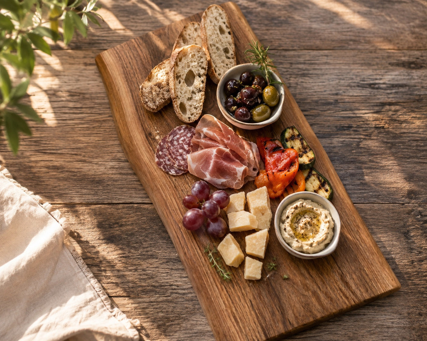 Mediterranes Sommerboard mit Burrata, gegrilltem Pfirsich, Prosciutto, Focaccia und Oliven auf massivem Holzbrett