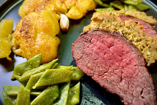 Perfekt gebratenes, medium-rare Roastbeef mit gewürzter Kruste, serviert mit grünen Bohnen und Röstkartoffeln.