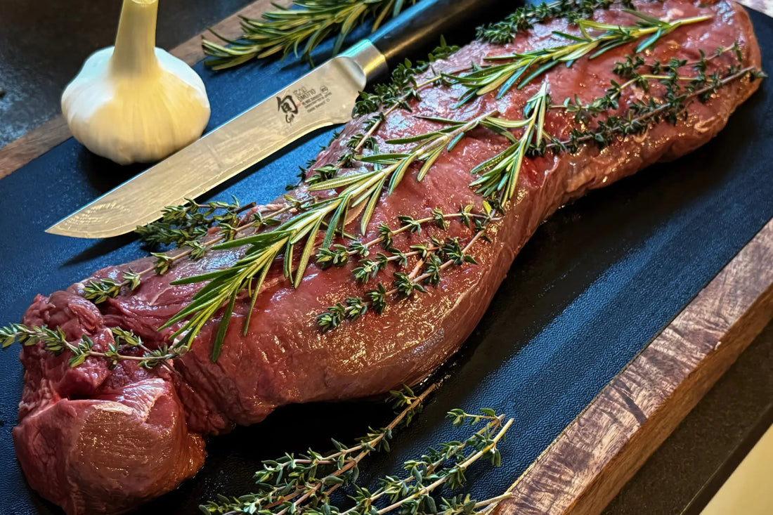 Rohe Rinderlende garniert mit frischen Rosmarin- und Thymianzweigen.