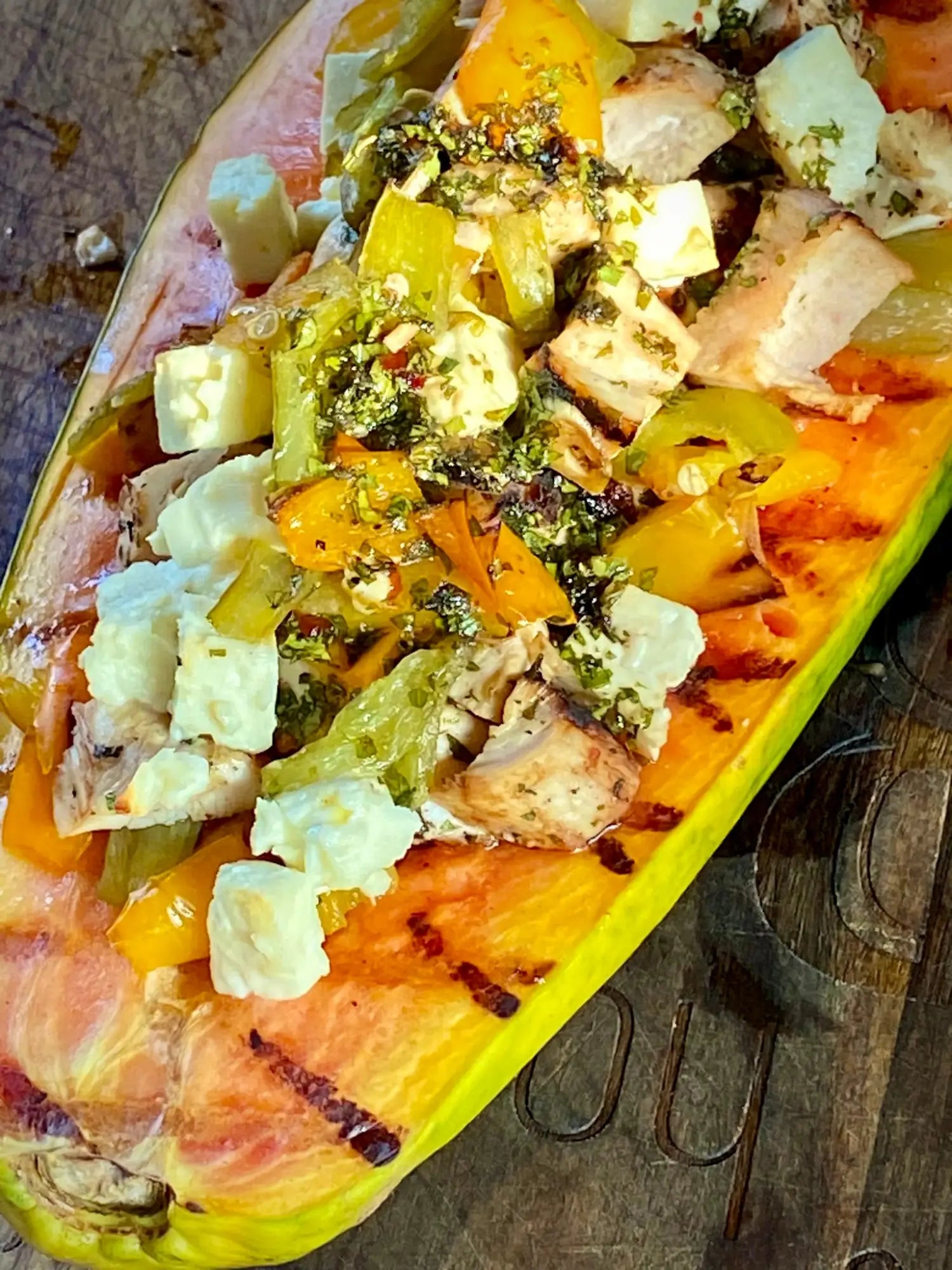 Gegrilltes Papayaboot, gefüllt mit einer bunten Salatmischung und zerbröckeltem Käse.