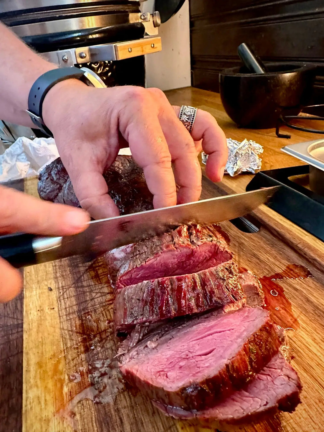 Perfekt gegartes medium-rare Steak, das auf einem Holzbrett in Scheiben geschnitten wird.