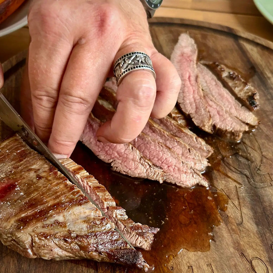 In Scheiben geschnittenes, medium-rare Rindfleisch auf einem Schneidebrett aus Holz.