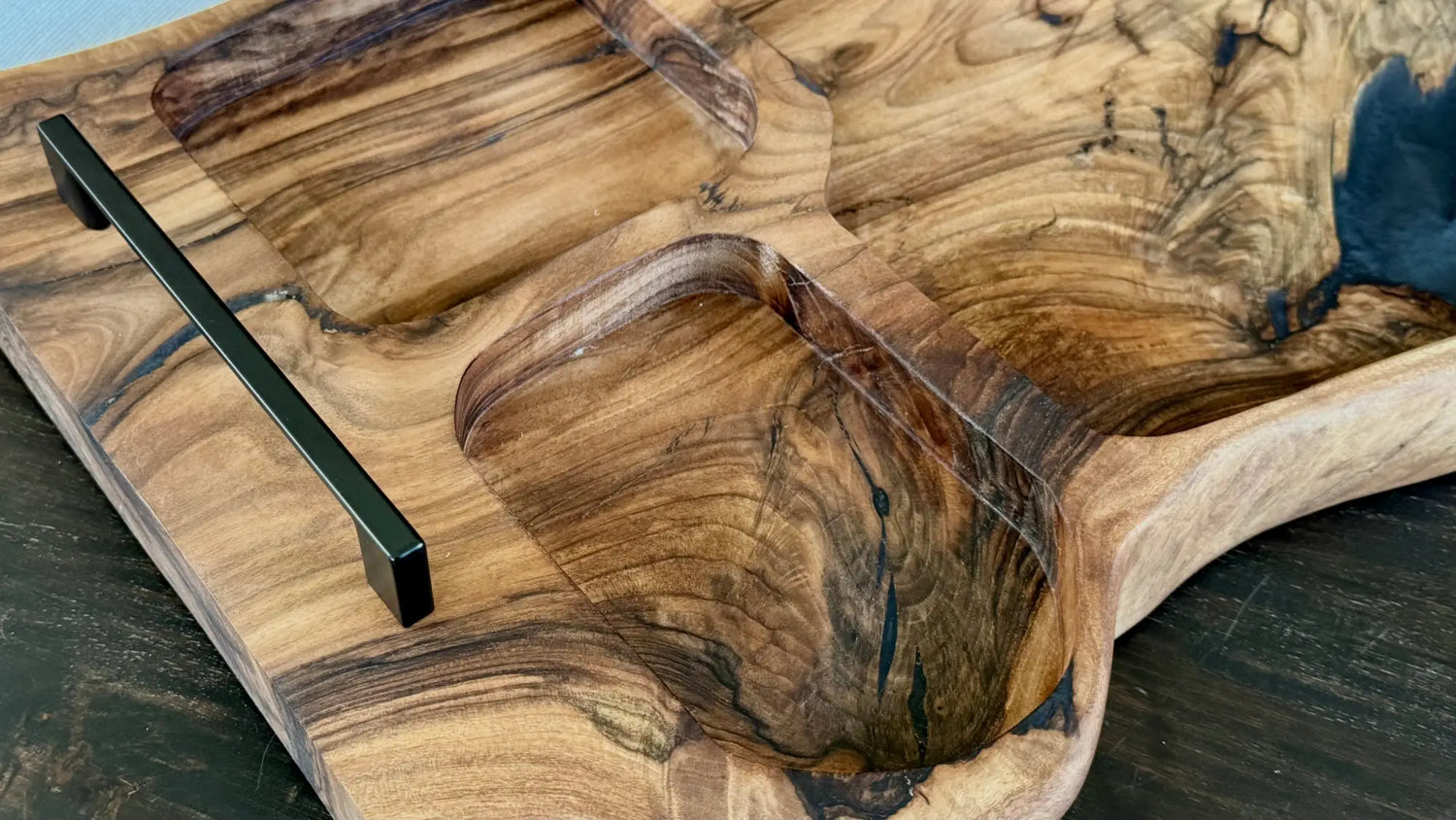 Ein hölzernes Serviertablett mit mehreren geschnitzten Fächern und einem dunklen Griff.