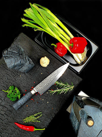Damast Chefmesser mit gehämmerter Klinge schneidet Fleisch auf Walnussholzbrett – ergonomischer FlameWOOD Griff sichtbar
