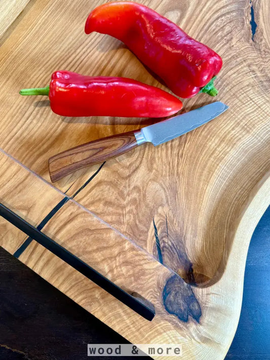 Zwei rote Paprika auf einem handgefertigten Eschenholz Servierbrett für die Küche
