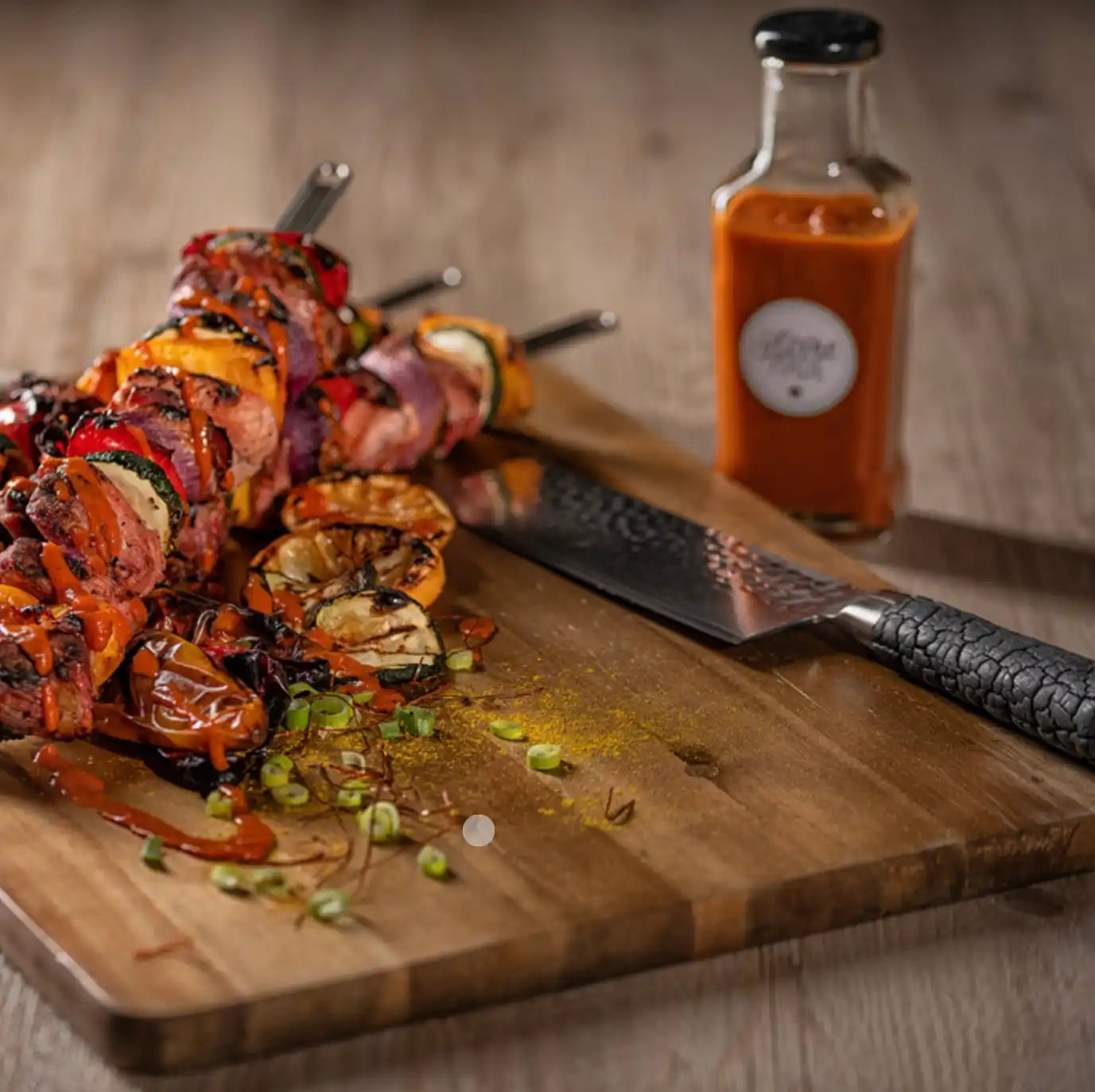 Gegrillte Fleisch- und Gemüsespieße mit einer Flasche Soße.