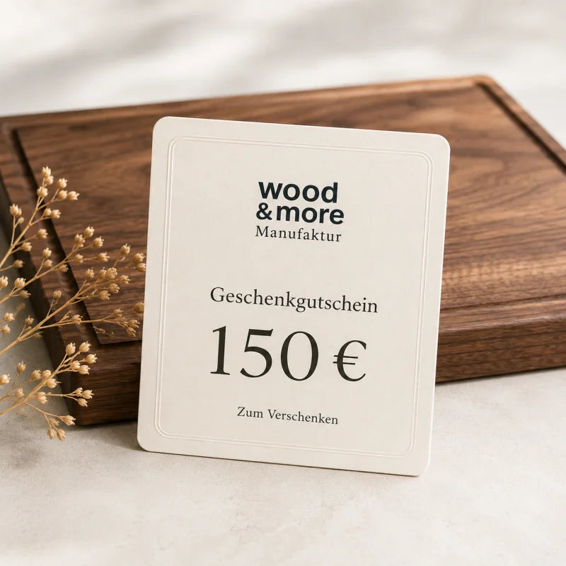 150 € Gutschein: wood & more Geschenkgutschein über 150 Euro vor einem hochwertigen Nussbaum-Schneidebrett