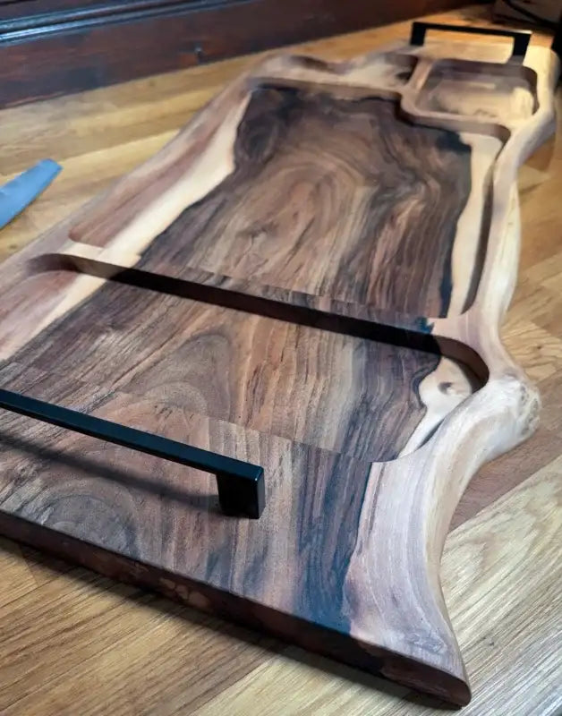 Holz-Servierplatte mit schwarzen Griffen und natürlichen Holzmaserungen.