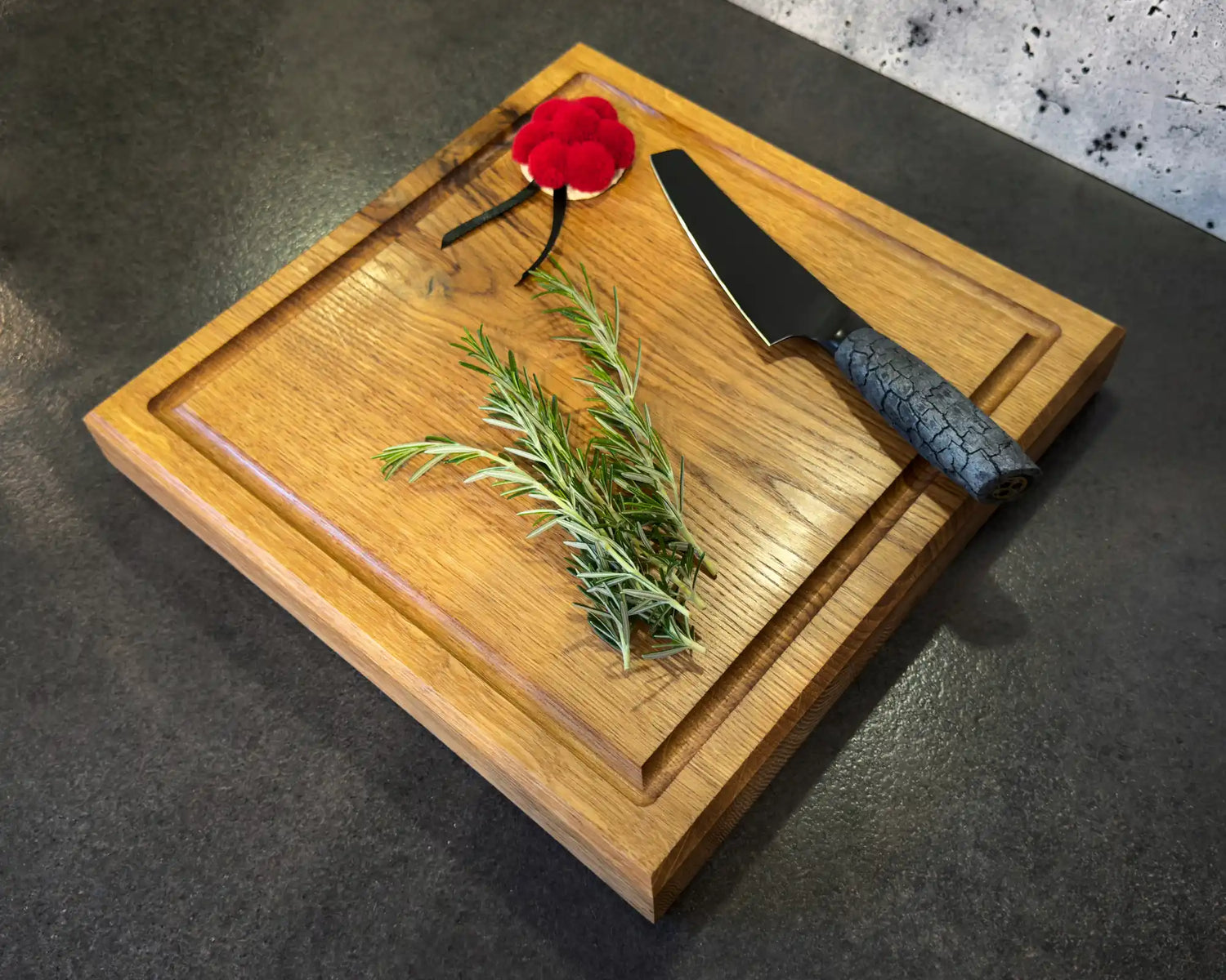 Ein Holzschneidebrett mit einem Messer und Rosmarinzweigen.