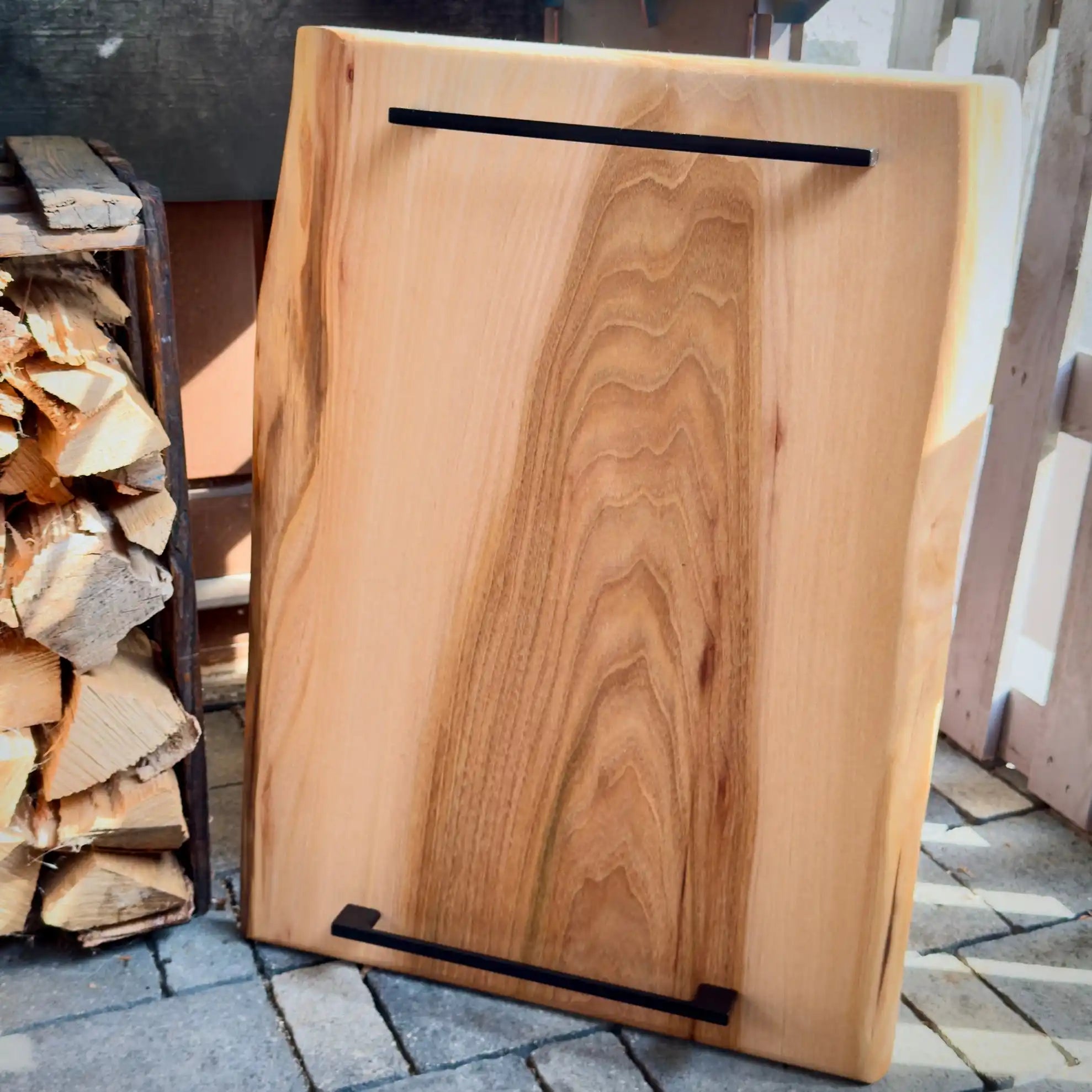 Lebendige Kante Holzscheibe mit schwarzen Metallgriffen.