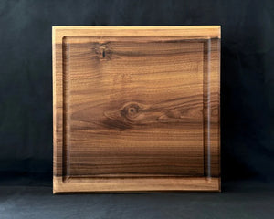 Massives Nussbaum-Schneidebrett 40 × 40 × 5 cm in frontaler Ansicht mit Saftrille und natürlicher dunkler Holzmaserung