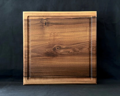 Massives Nussbaum-Schneidebrett 40 × 40 × 5 cm in frontaler Ansicht mit Saftrille und natürlicher dunkler Holzmaserung