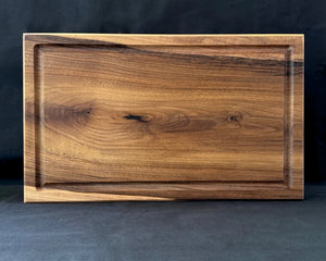Massives Nussbaum-Schneidebrett 50 × 30 × 5 cm in frontaler Ansicht mit Saftrille und länglicher Arbeitsfläche