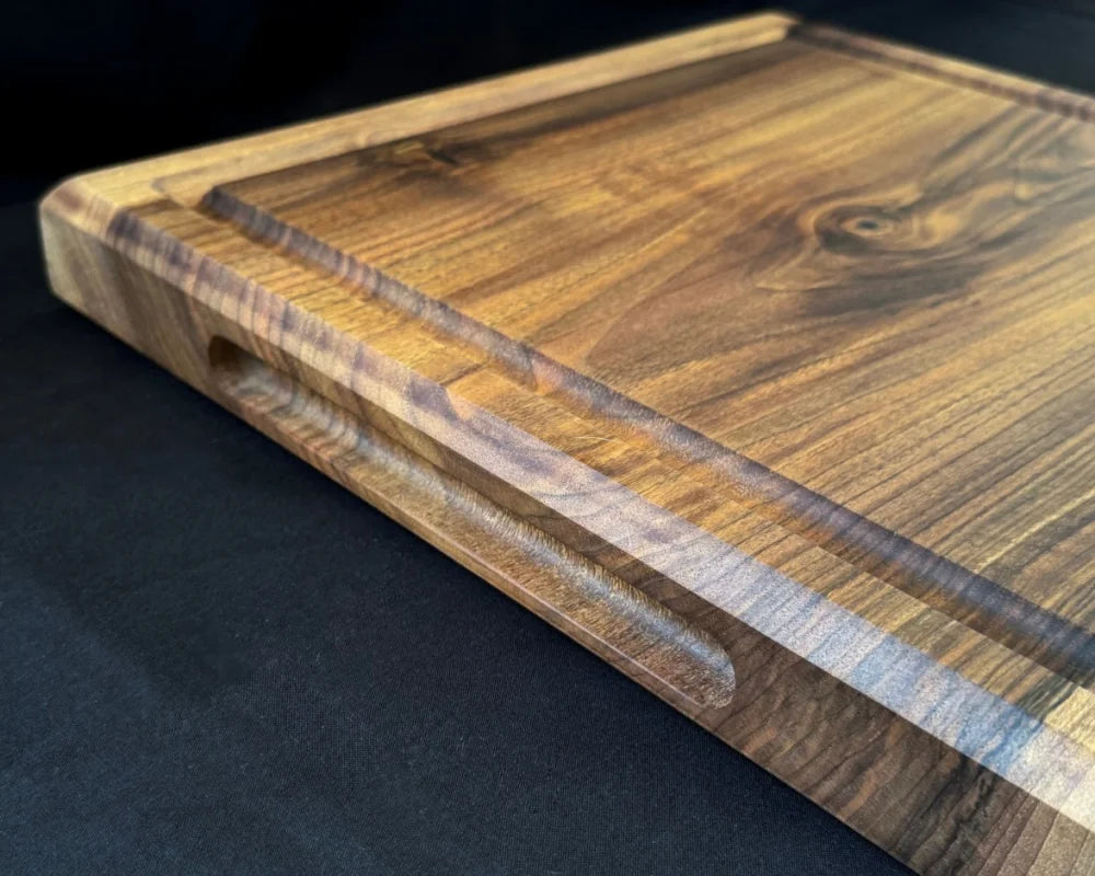 Seitliche Griffmulde am 5 cm starken Nussbaum-Schneidebrett 50 × 50 cm für einfaches Anheben und sicheres Tragen