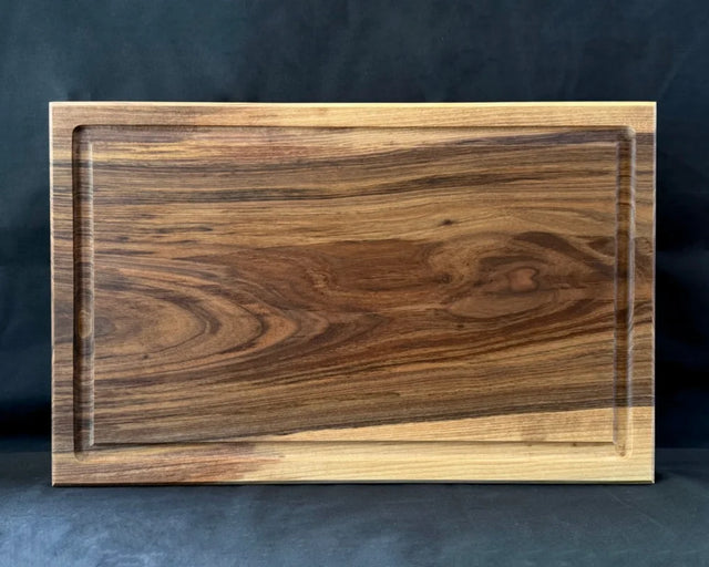 Großes massives Nussbaum-Schneidebrett 60 × 40 × 5 cm in frontaler Ansicht mit Saftrille und kräftiger Maserung