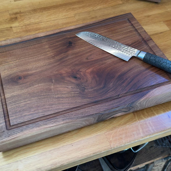 Video zeigt das Premium Chefbrett aus massivem Nussbaum mit Damastmesser – 4 cm stark, mit Saftrille. Detailzoom auf Maserung & Verarbeitung.
