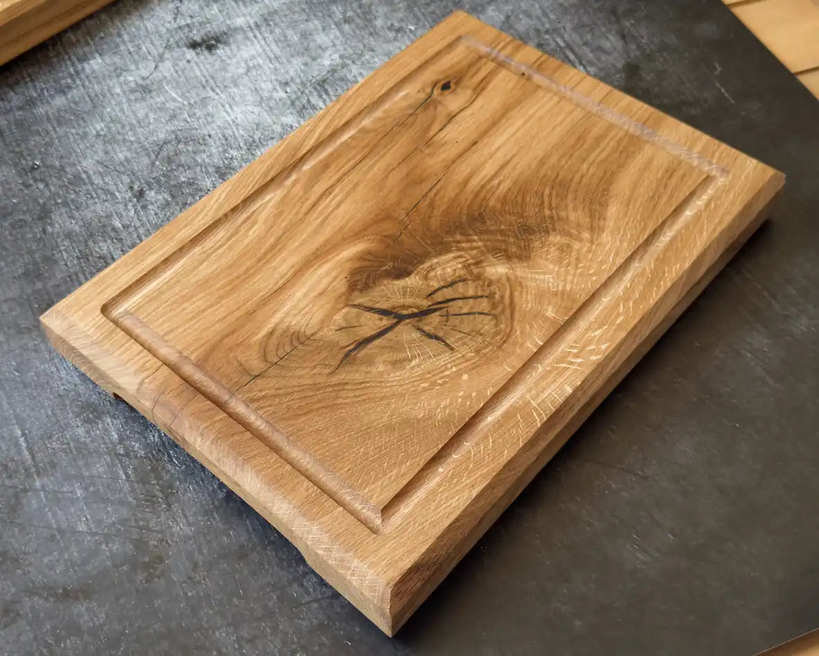 Rechteckiges Schneidebrett aus Holz mit Saftgut und ausgeprägter natürlicher Holzmaserung.