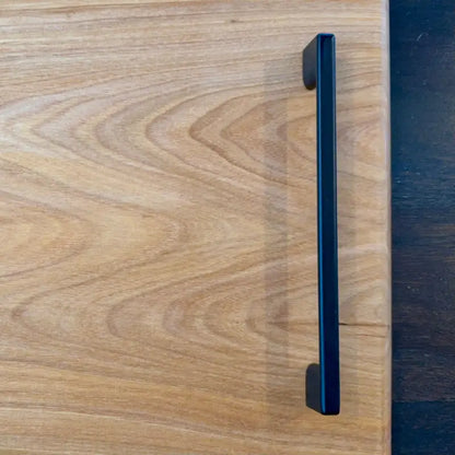 Schwarzer Metallgriff auf hellem Holz für UNIKAT BBQ Schneidebrett massivholz grill