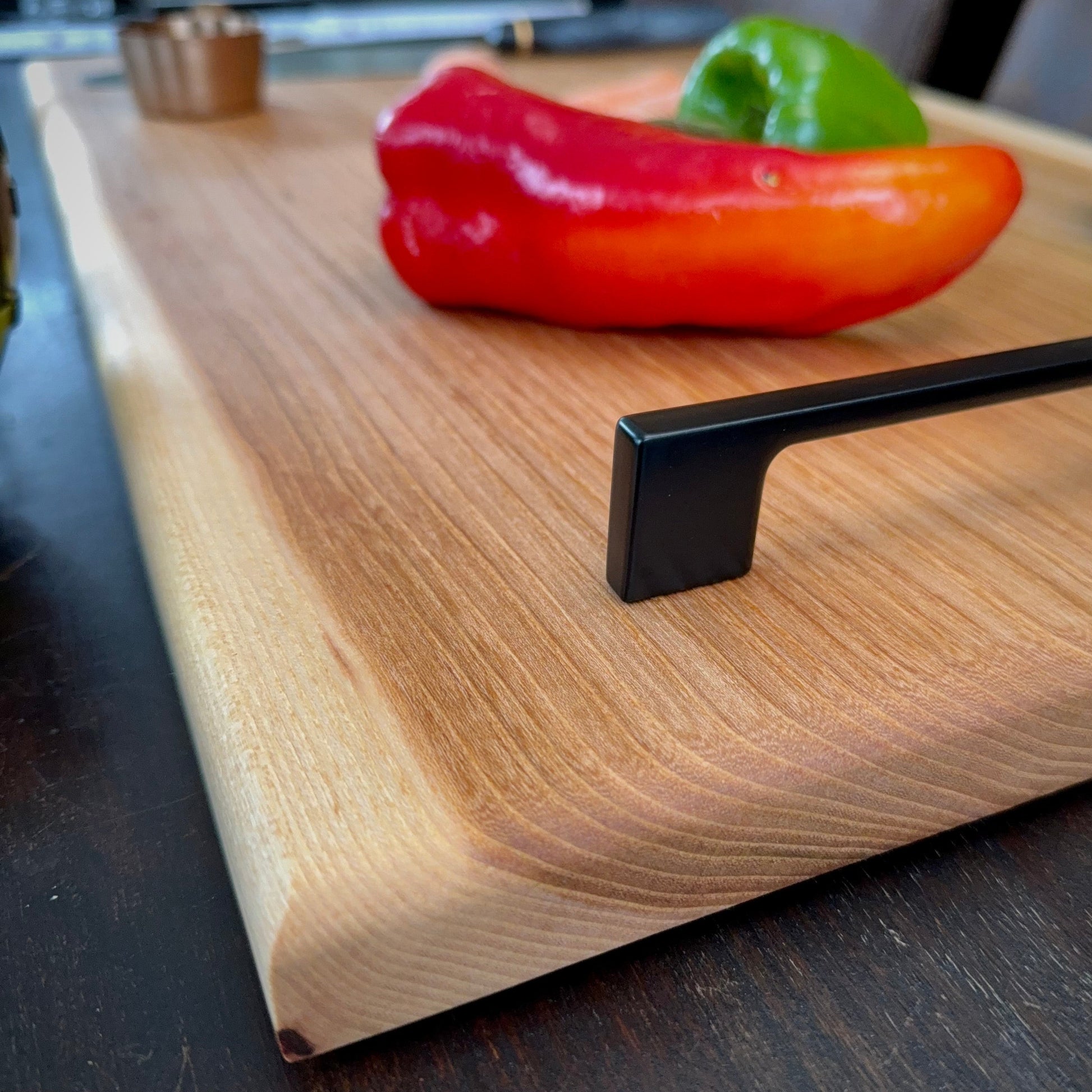 Rot- und orangefarbener Paprika auf einem Holz Servierbrett mit Füßen
