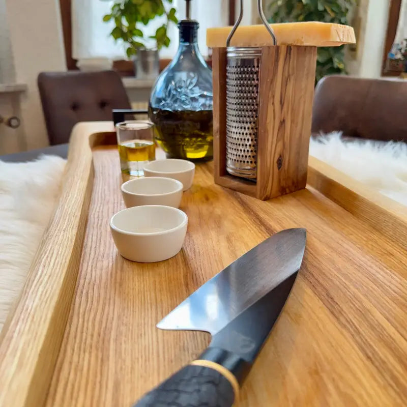 Chefmesser mit dunklem Griff und goldener Akzentfassung auf UNIKAT Holz Servierbrett XXL