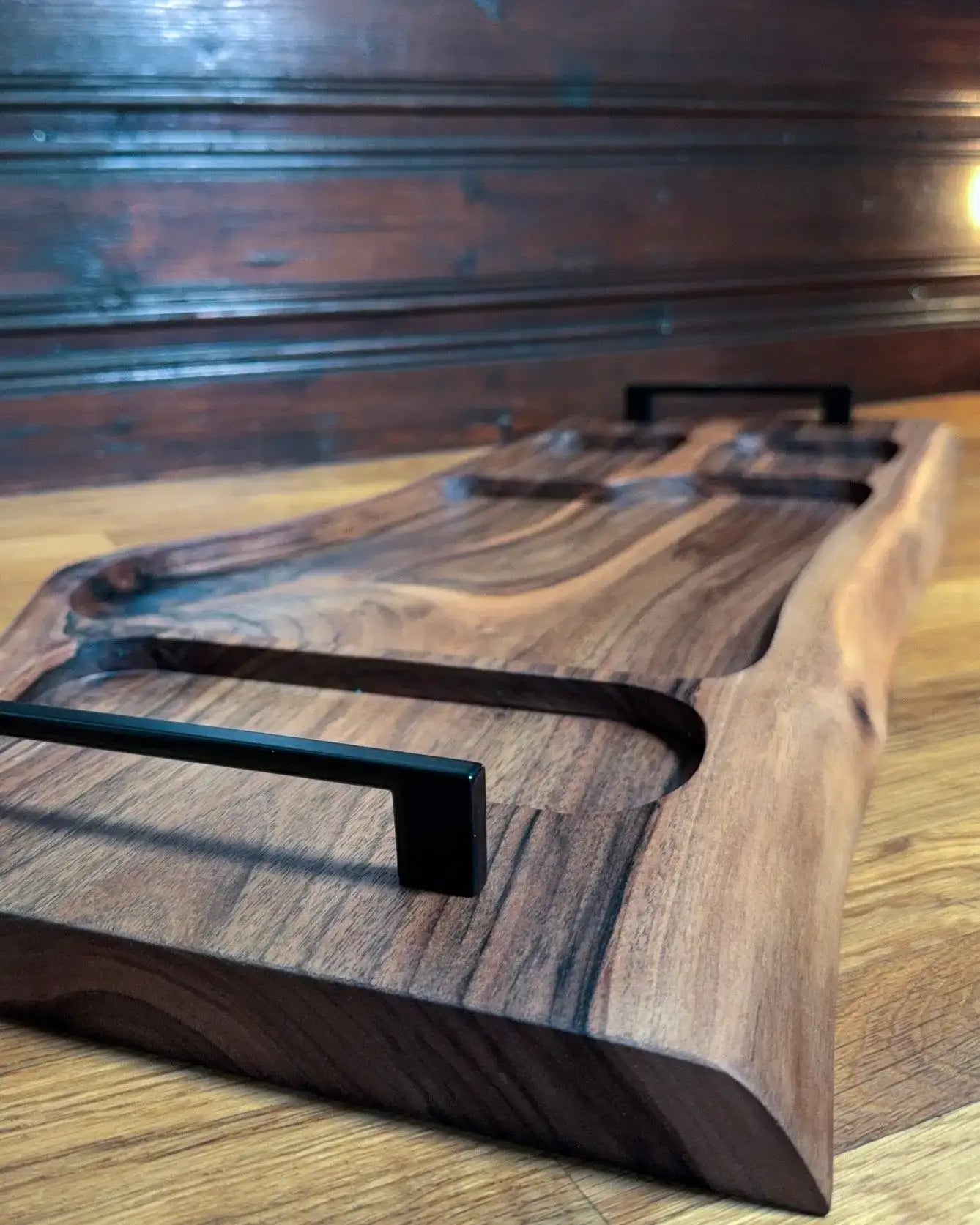 Walnuss-Servierplatte mit schwarzen Griffen und natürlicher Holzmaserung.