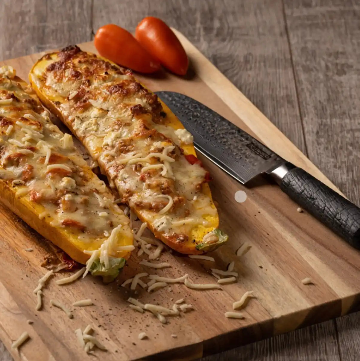 Zwei Hälften gebackener Zucchini, gefüllt mit einer käsigen, herzhaften Füllung.
